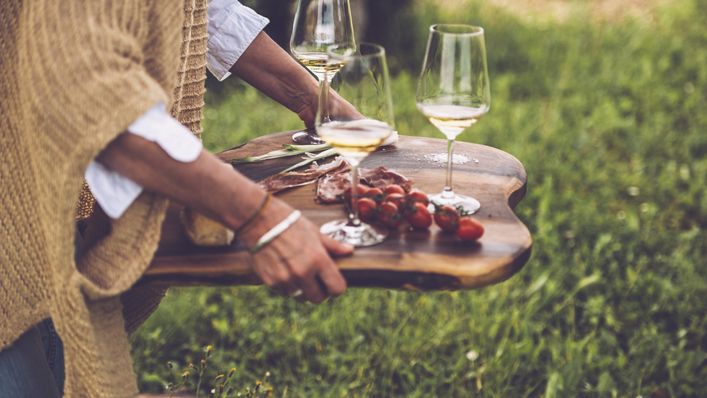 Glasses of wine and cherry tomatoes on a wooden serving tray