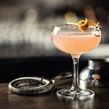  Orange alcoholic cocktail drink Cosmopolitan decorated with orange peel on bar counter