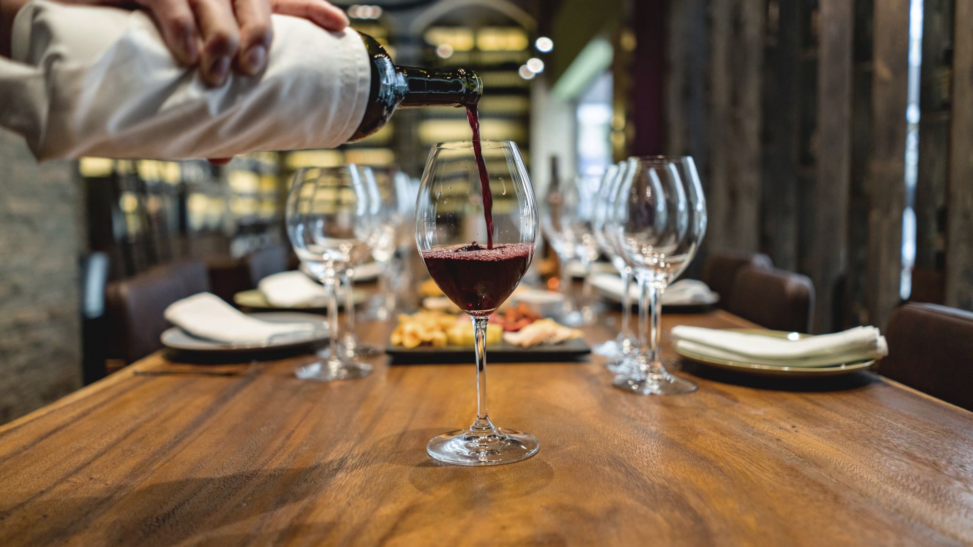 Close-up on a sommelier serving red wine at a winetasting â   food and drinks concepts