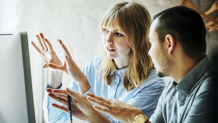 Two startup business colleagues problem-solving at a computer together in the office.